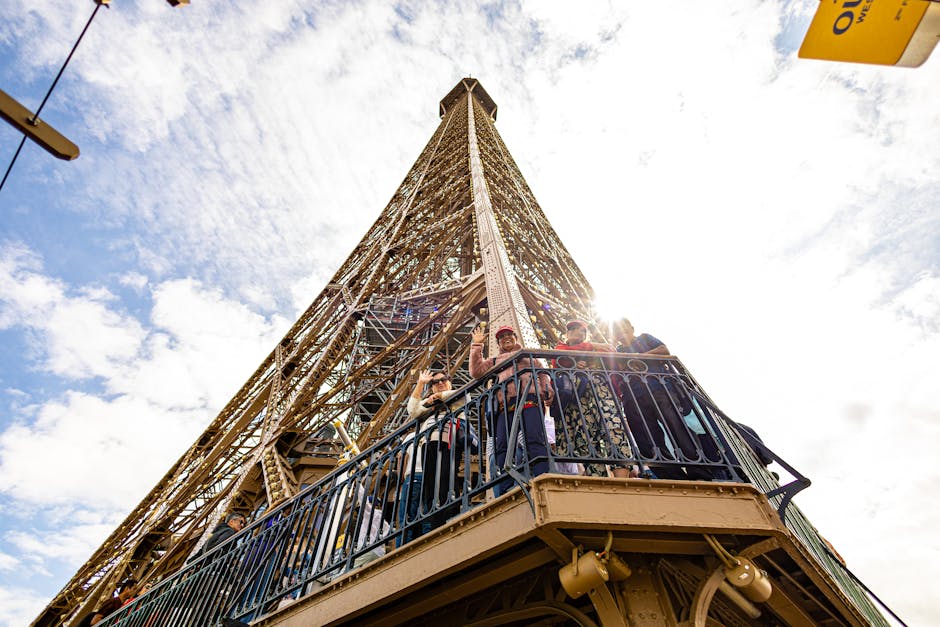 A stunning upward shot of the Eiffel Tower with visitors enjoying the view on a sunny day.