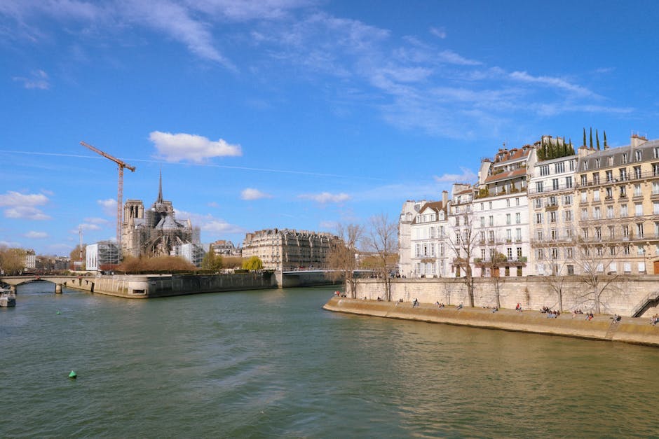 Bright daytime scene of the Seine River with Notre-Dame and Parisian buildings, showcasing iconic Paris architecture.